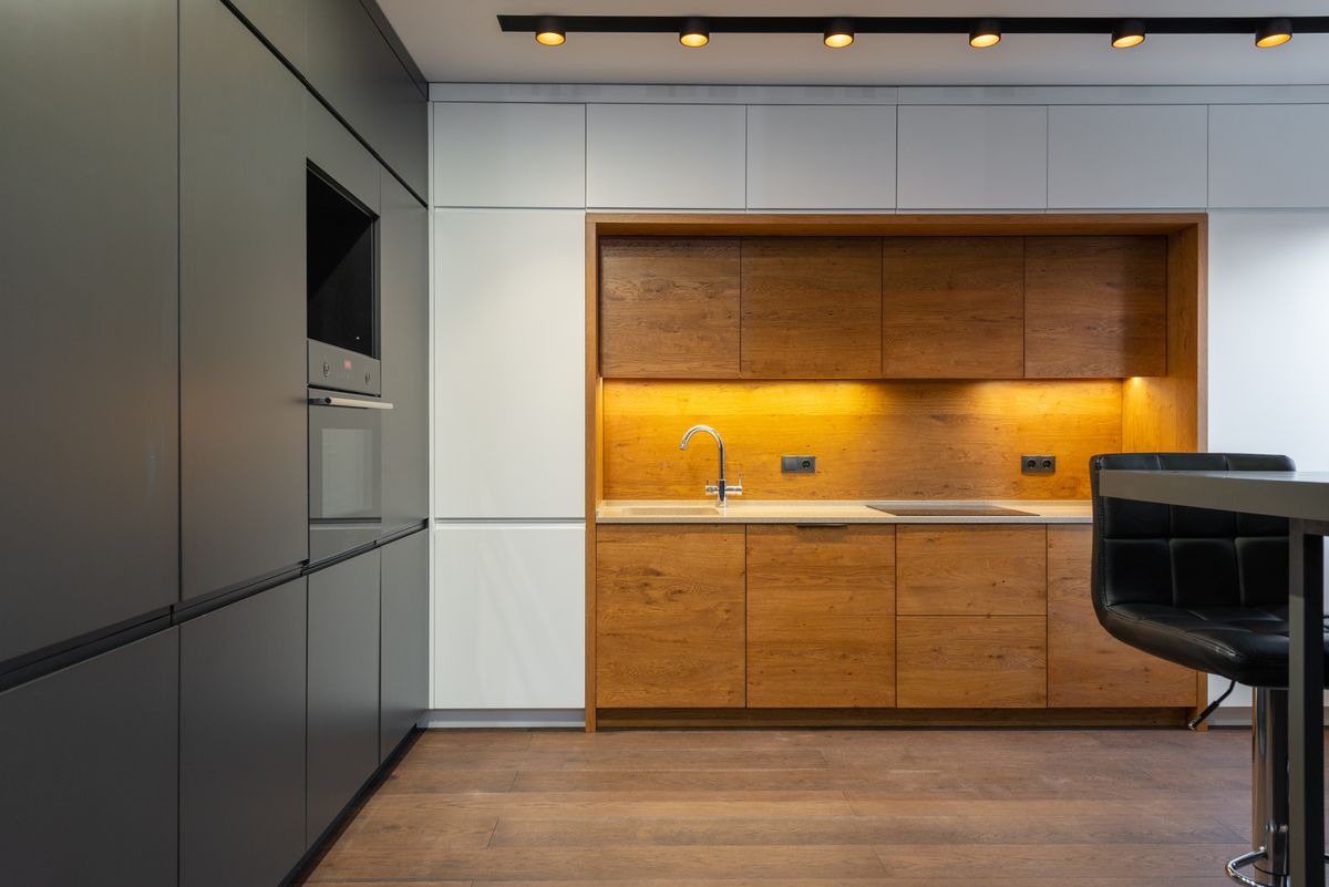 A dark handleless kitchen with an oak-lined niche