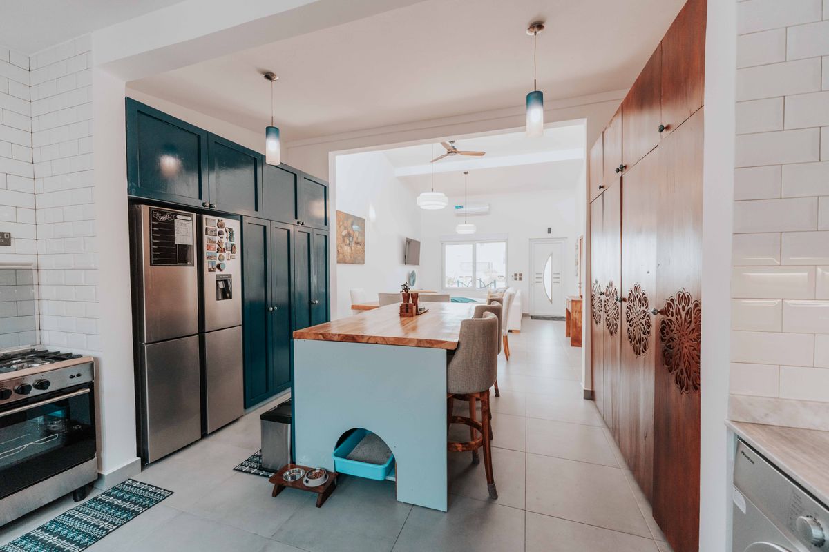 An open-plan kitchen with teal fronts and a central island